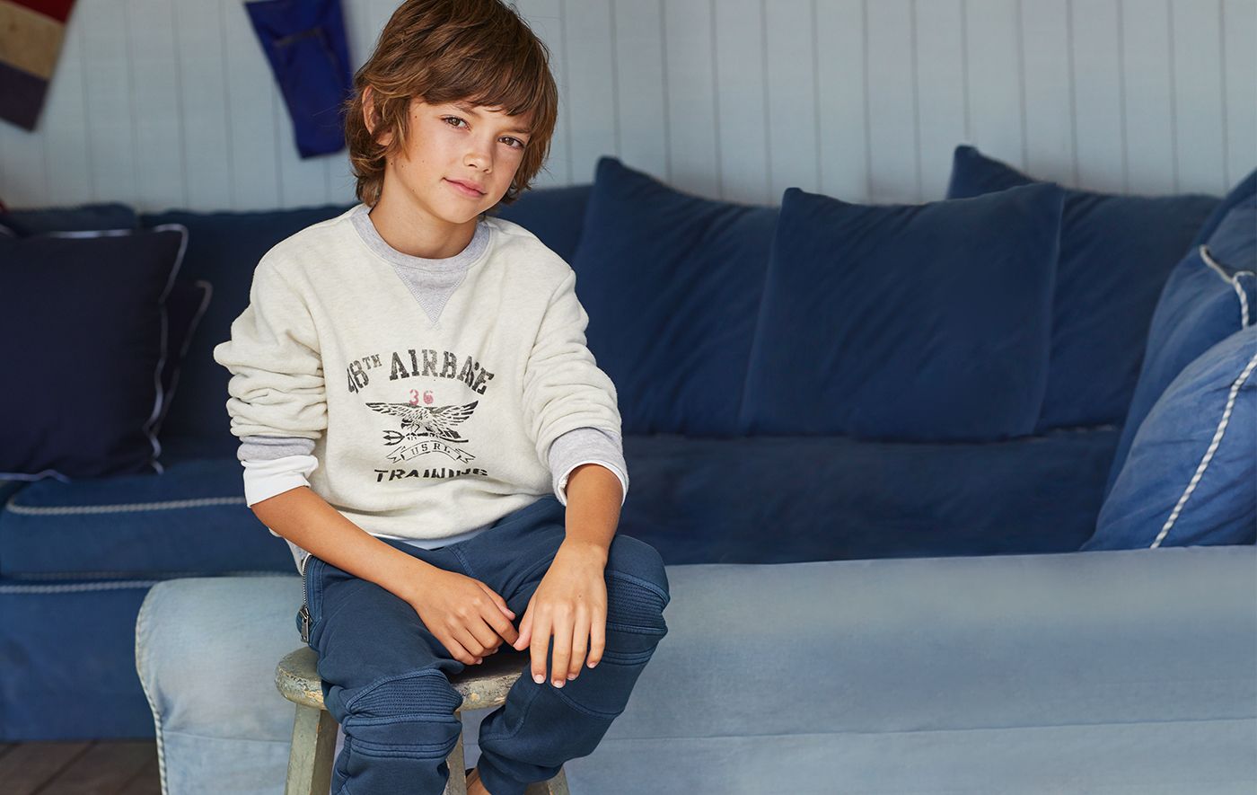 Boy in white graphic sweatshirt & grey moto jogger pants